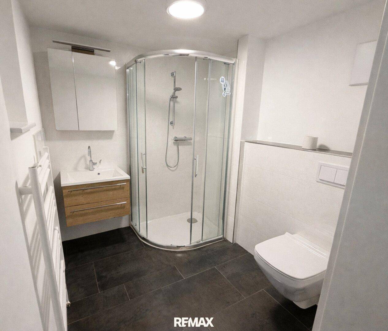 Badezimmer im Untergeschoss mit Eckdusche, WC, Waschbecken und beheiztem Handtuchhalter.