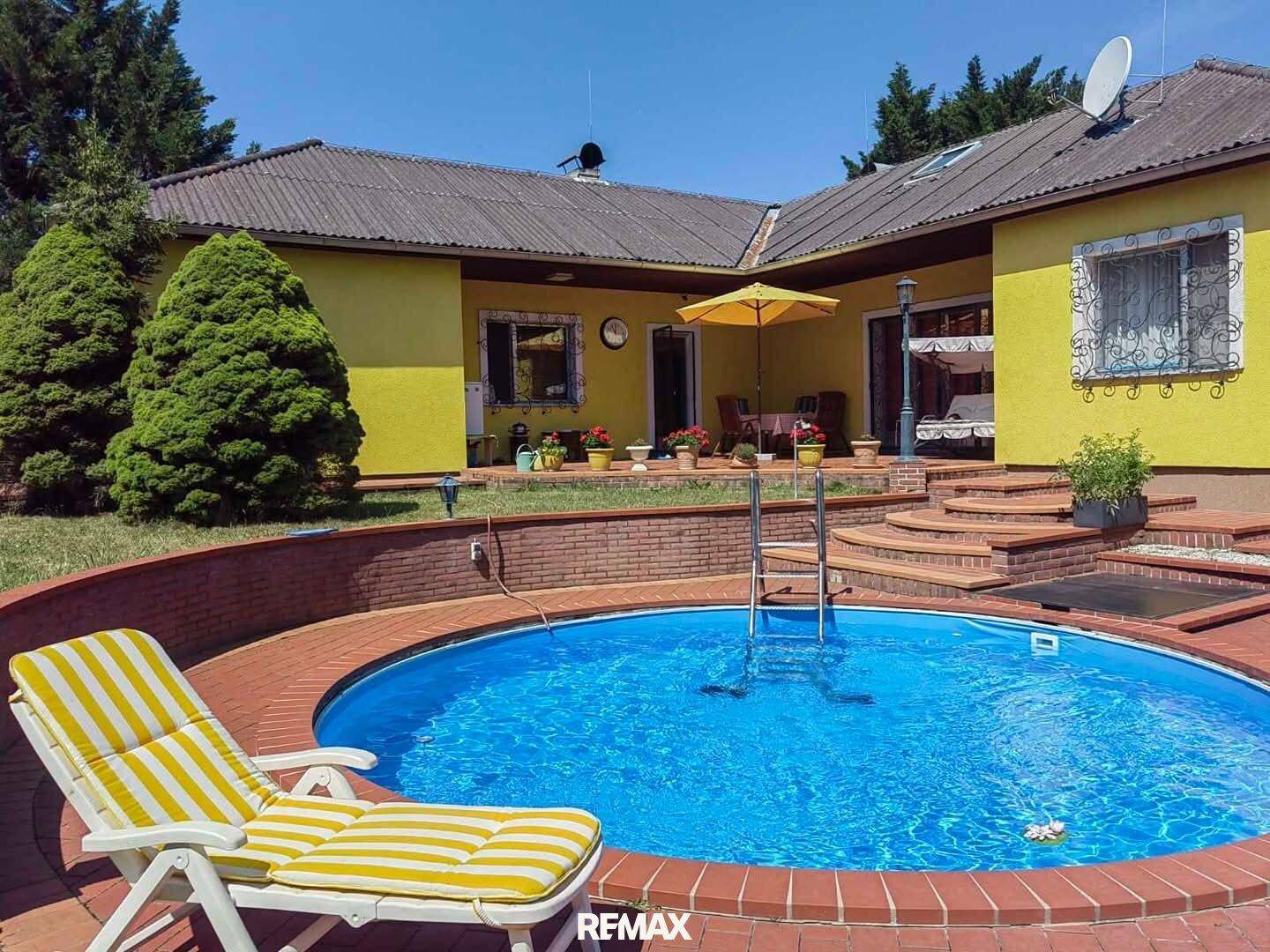 Detailansicht des Pools mit Liegestuhl und angrenzender Terrasse, ideal zum Entspannen.