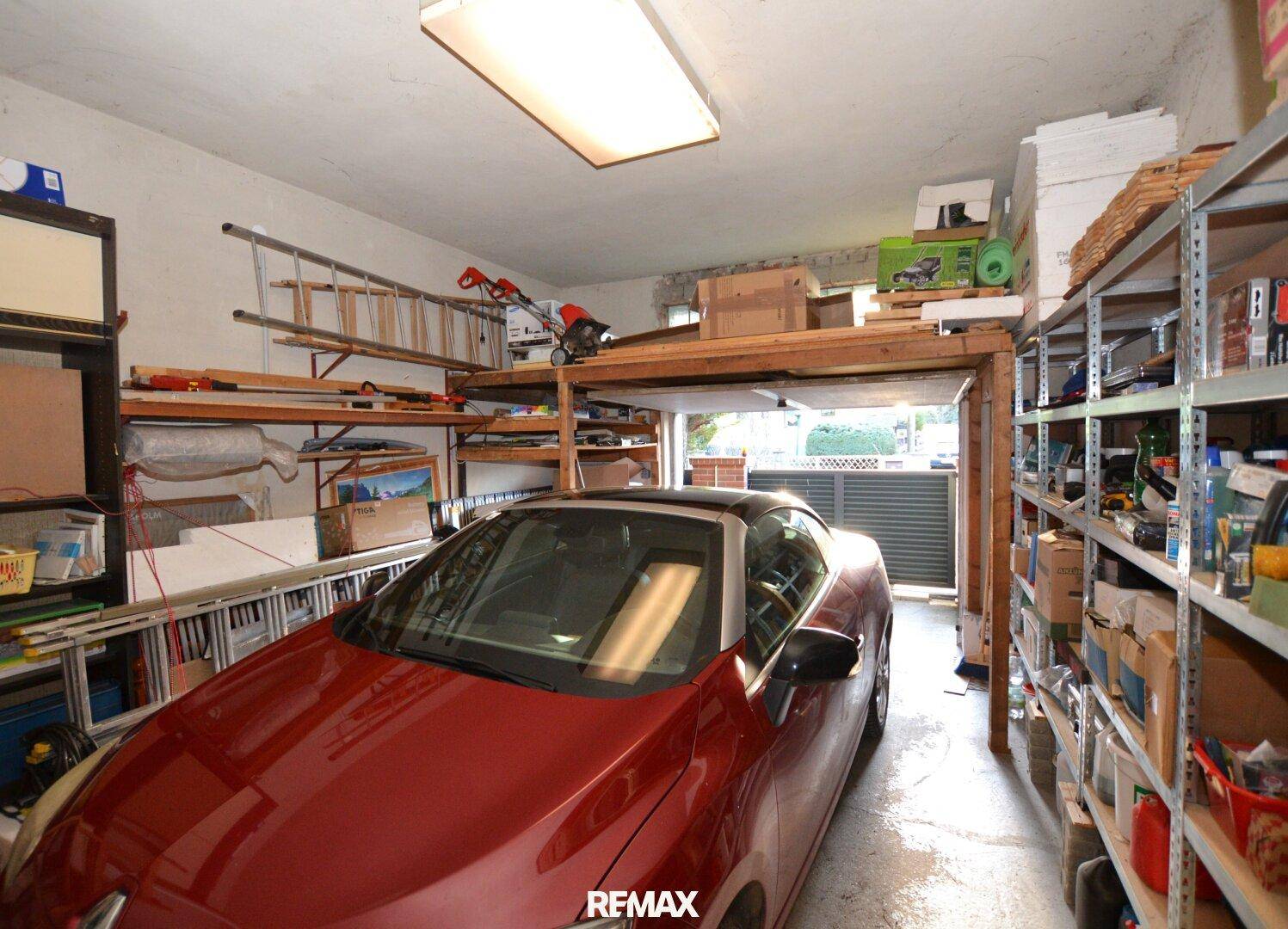 Geräumige Garage mit einem Auto, Regalen und Stauraum für Werkzeuge und Geräte.