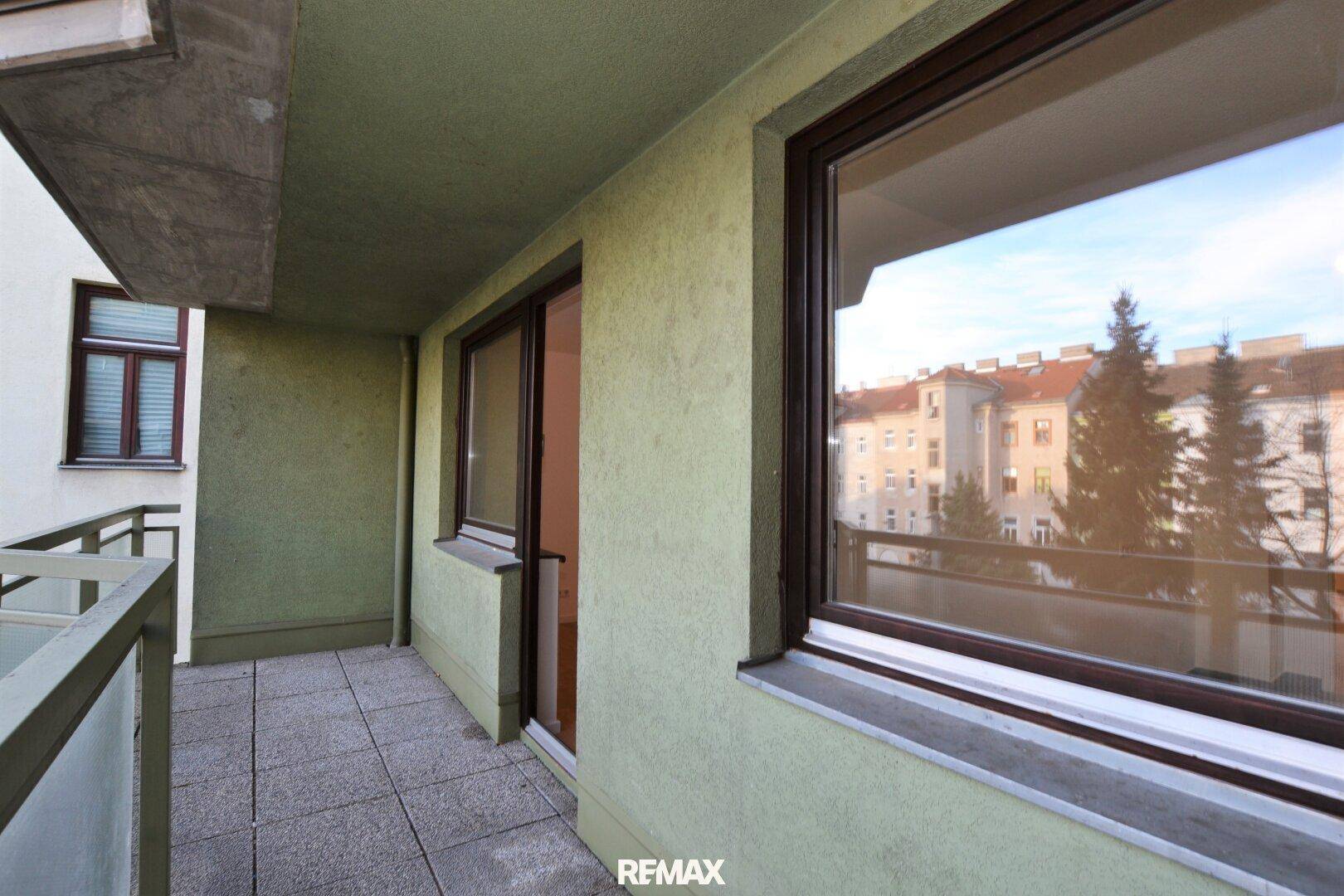 Balkon mit Fliesenboden und Blick auf die umliegenden Gebäude.