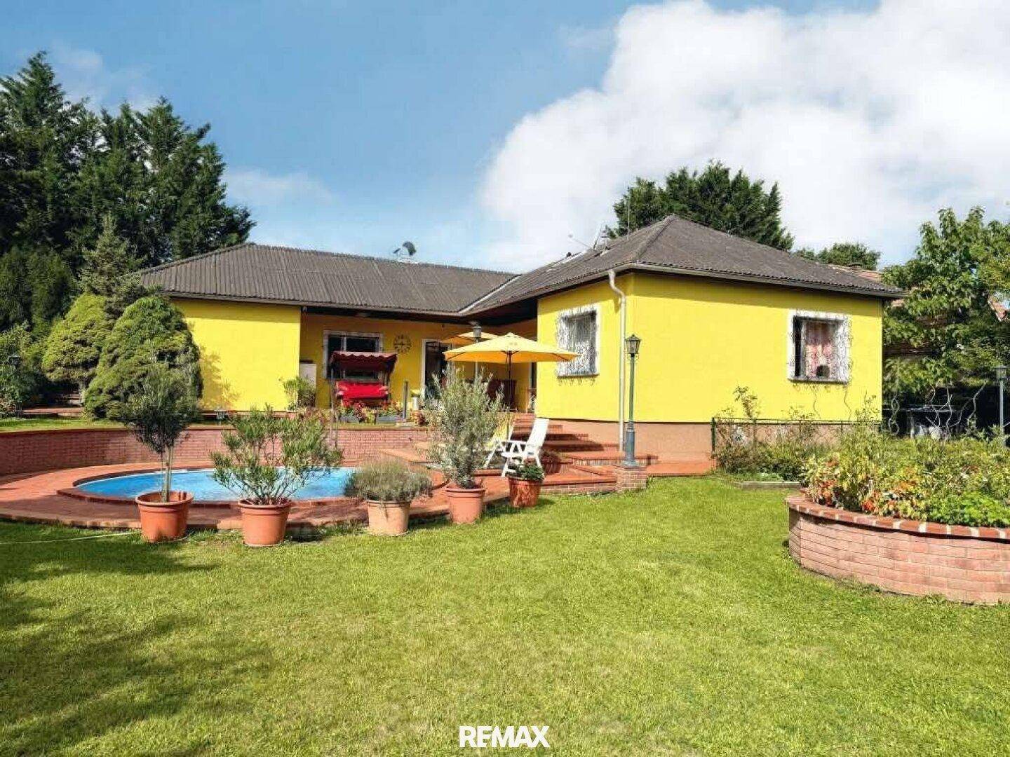 Ansicht des Hauses von der Gartenseite mit Pool, Terrasse und gepflegter Rasenfläche.