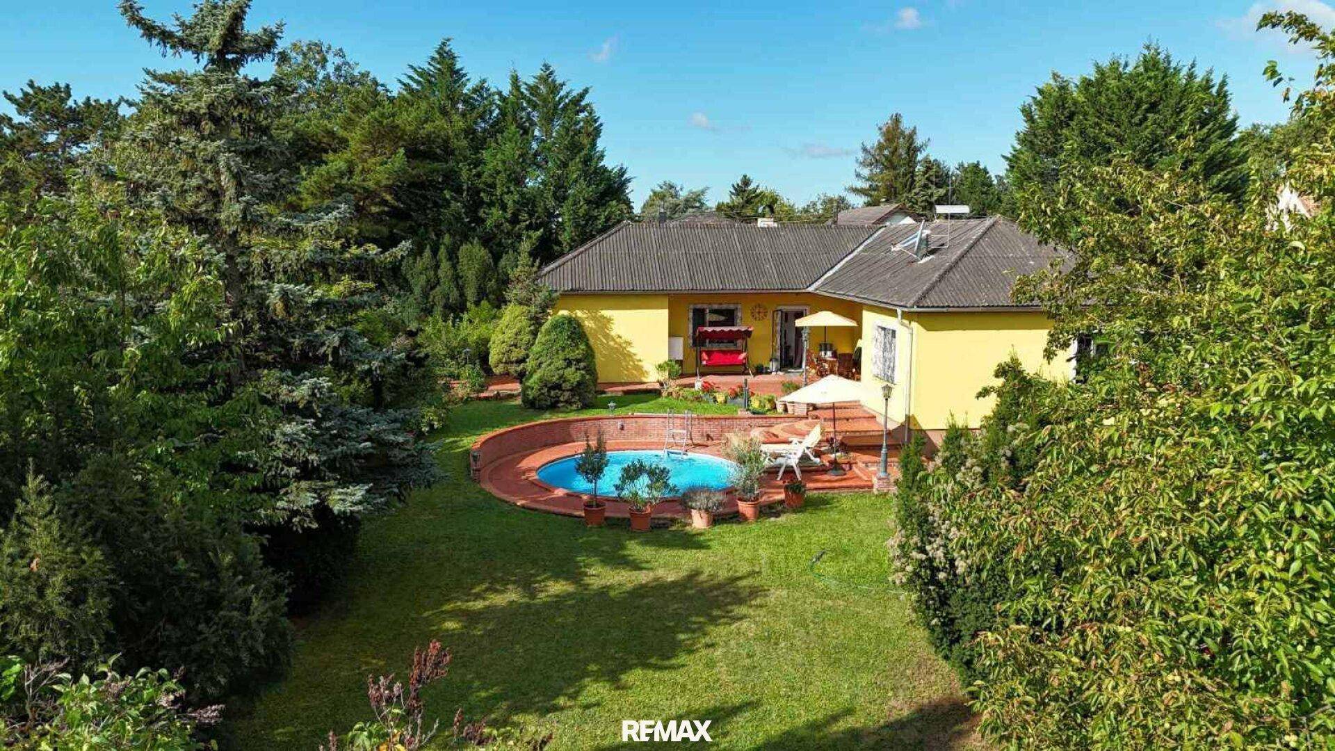 Weitläufiger Garten mit Pool und Haus, umgeben von hohen Bäumen und viel Privatsphäre.