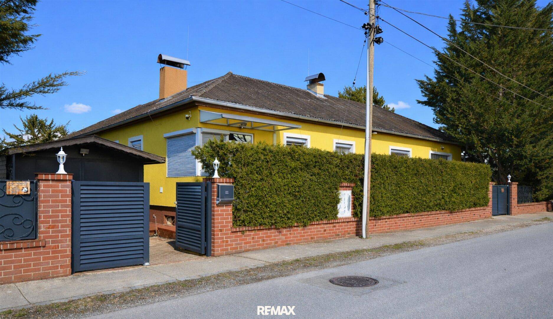 Ansicht des Hauses von der Straße mit gepflegter Hecke und modernem Eingangstor.