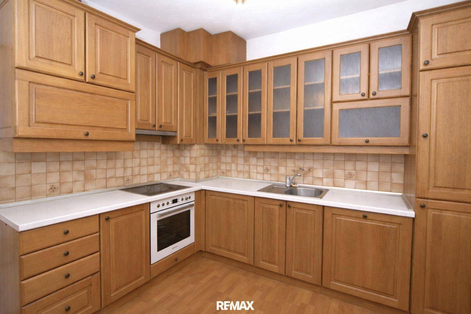 Funktionale Holzküche mit Einbaugeräten, Fliesenrückwand und ausreichend Arbeitsfläche.