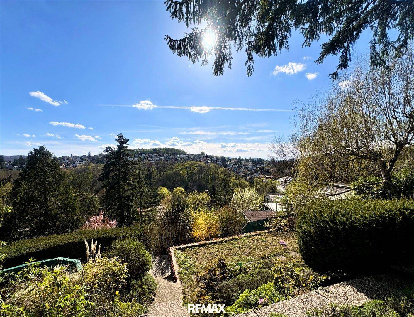 Terrassierter Gartenbereich mit Stufen und weitem Blick über die grüne Landschaft und die umliegende Siedlung.