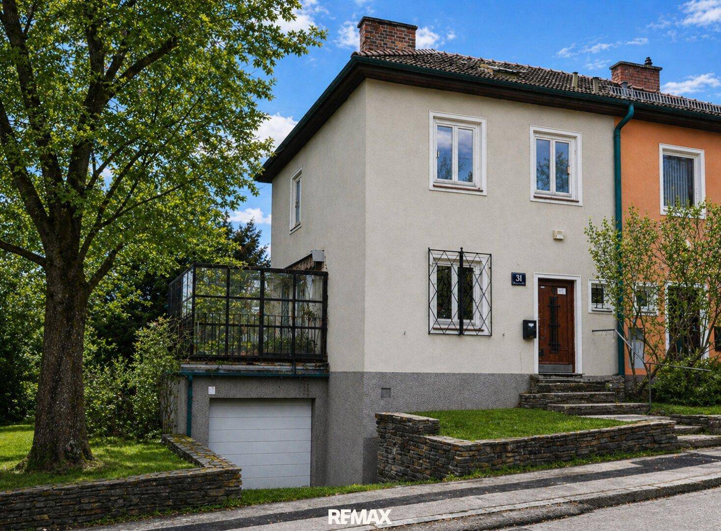 Vorderansicht eines Einfamilienhauses mit Garage im Untergeschoss und kleinem Vorgarten.