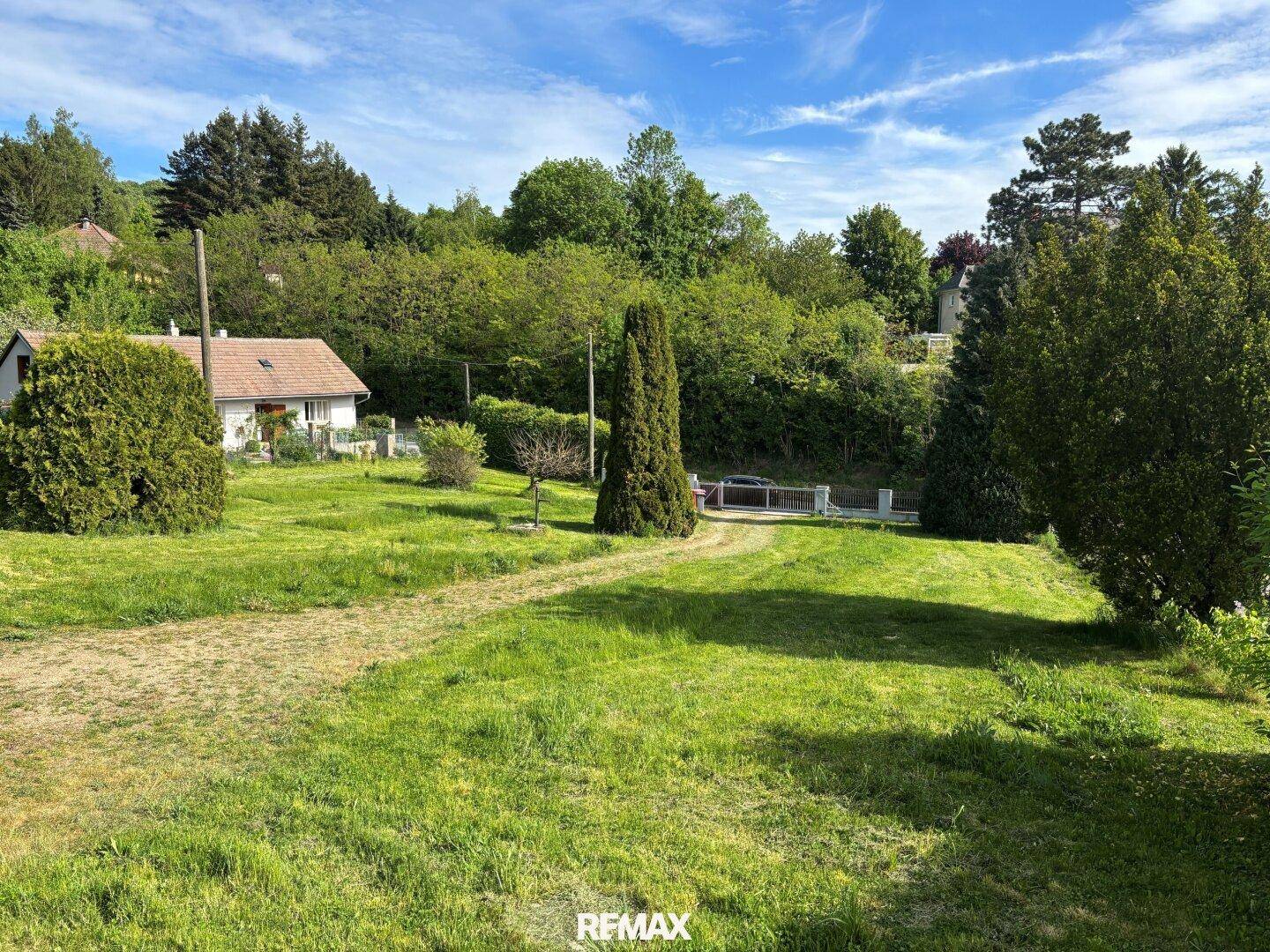 Weitläufiger Gartenbereich mit Rasenfläche und Bäumen, umgeben von ländlicher Natur.