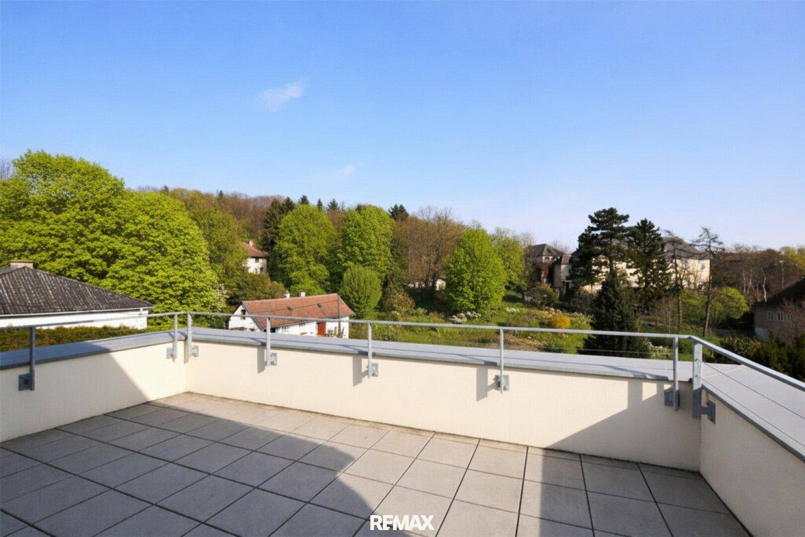 Geräumige Dachterrasse mit Fliesenboden und weitem Blick über die grüne Umgebung.