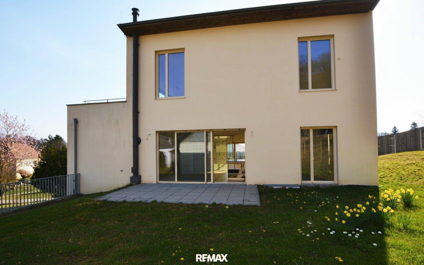 Rückseite des Hauses mit Terrasse, Rasenfläche und Zugang zum Garten.