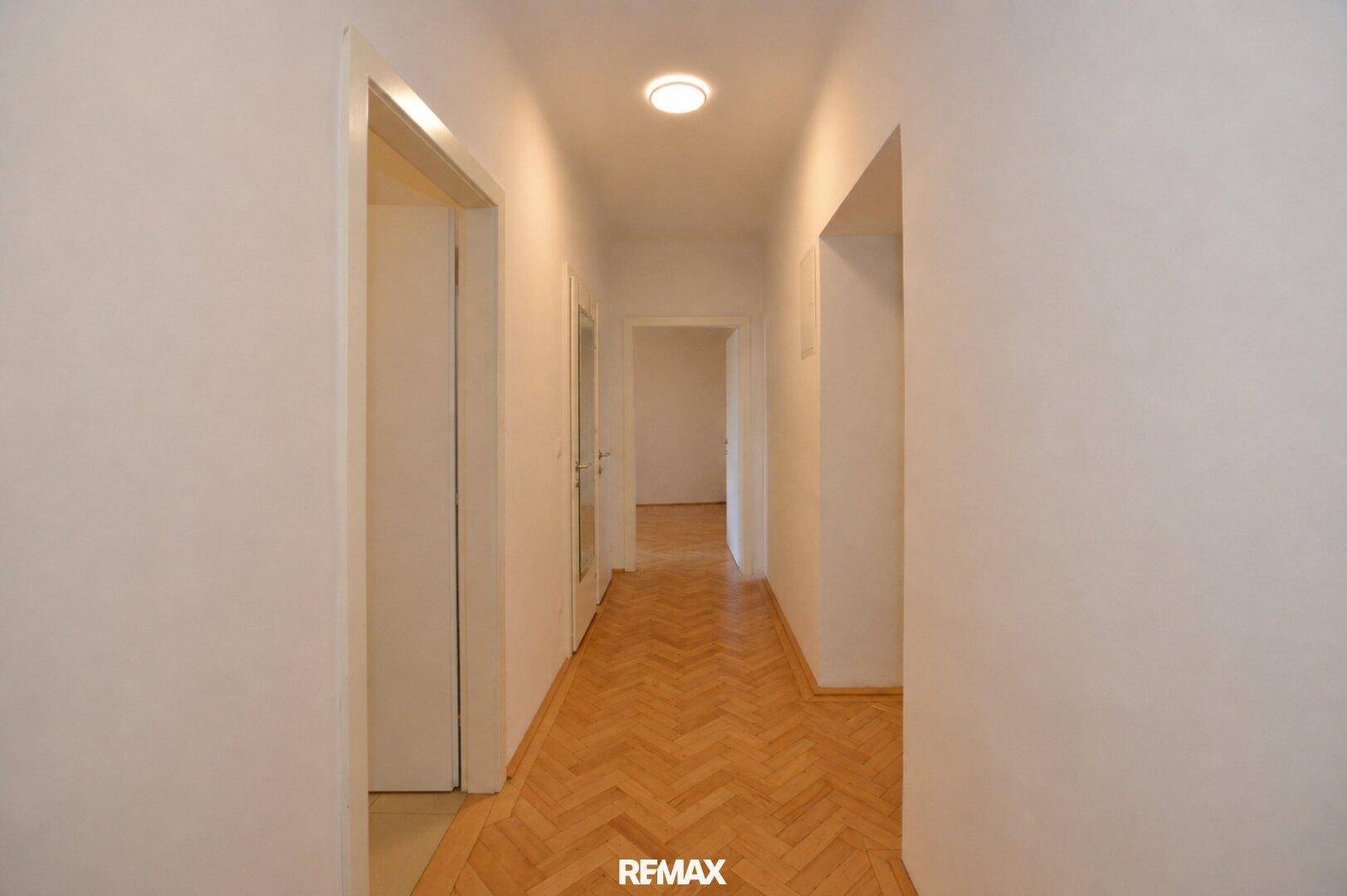 Heller Flur mit Parkettboden und weißen Wänden, verbindet die verschiedenen Räume der Wohnung.