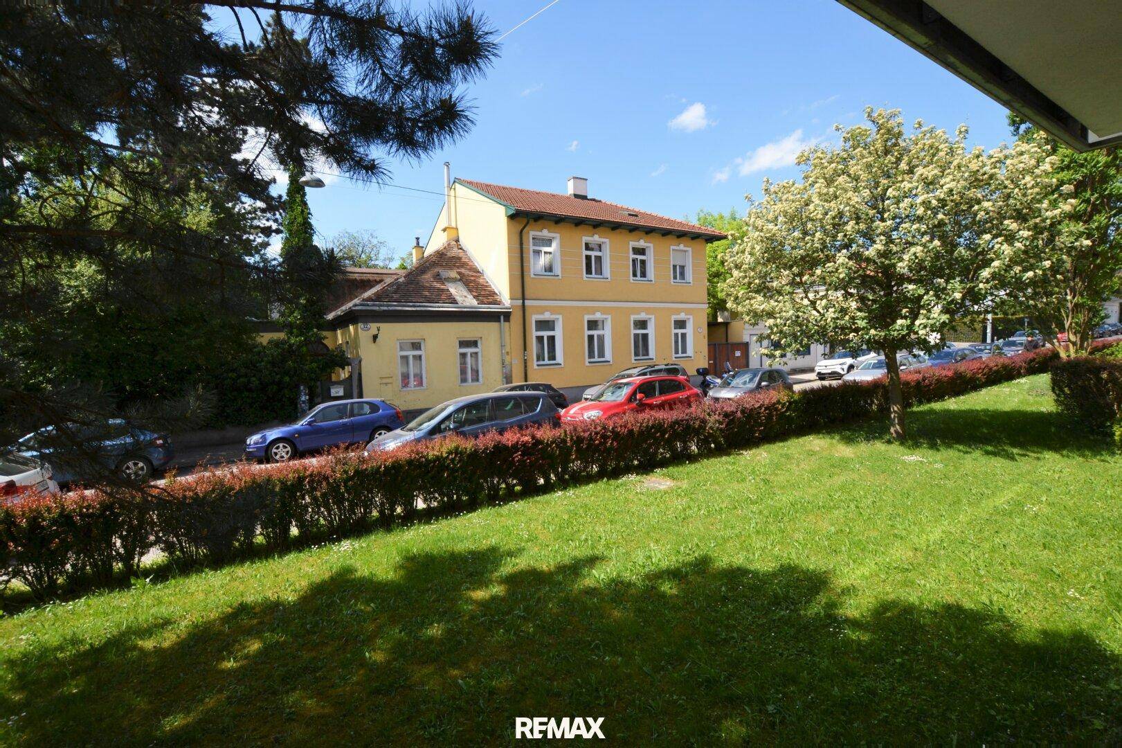 Blick auf eine ruhige Wohnstraße mit parkenden Autos und einem charmanten gelben Gebäude.