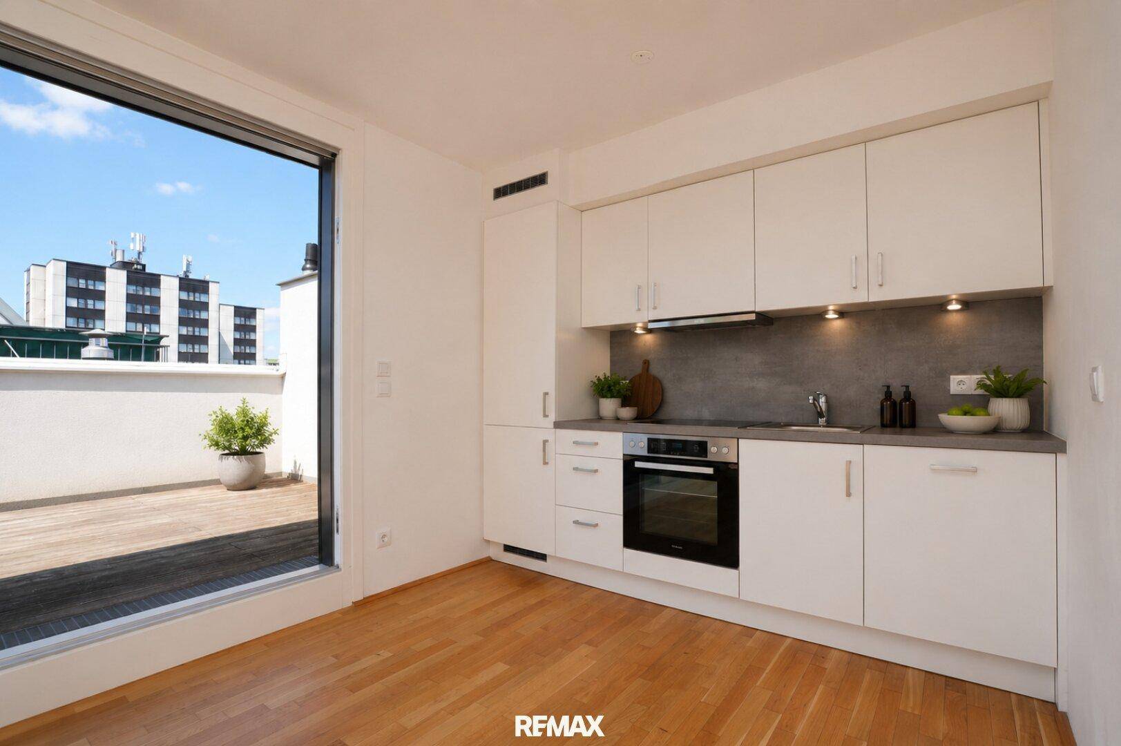 Helle Einbauküche mit weißen Fronten, modernen Geräten und Blick auf die Stadt.