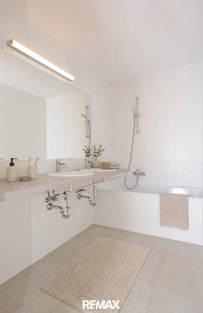 Modernes Badezimmer mit breitem Waschbecken, Badewanne und hellen Fliesen.