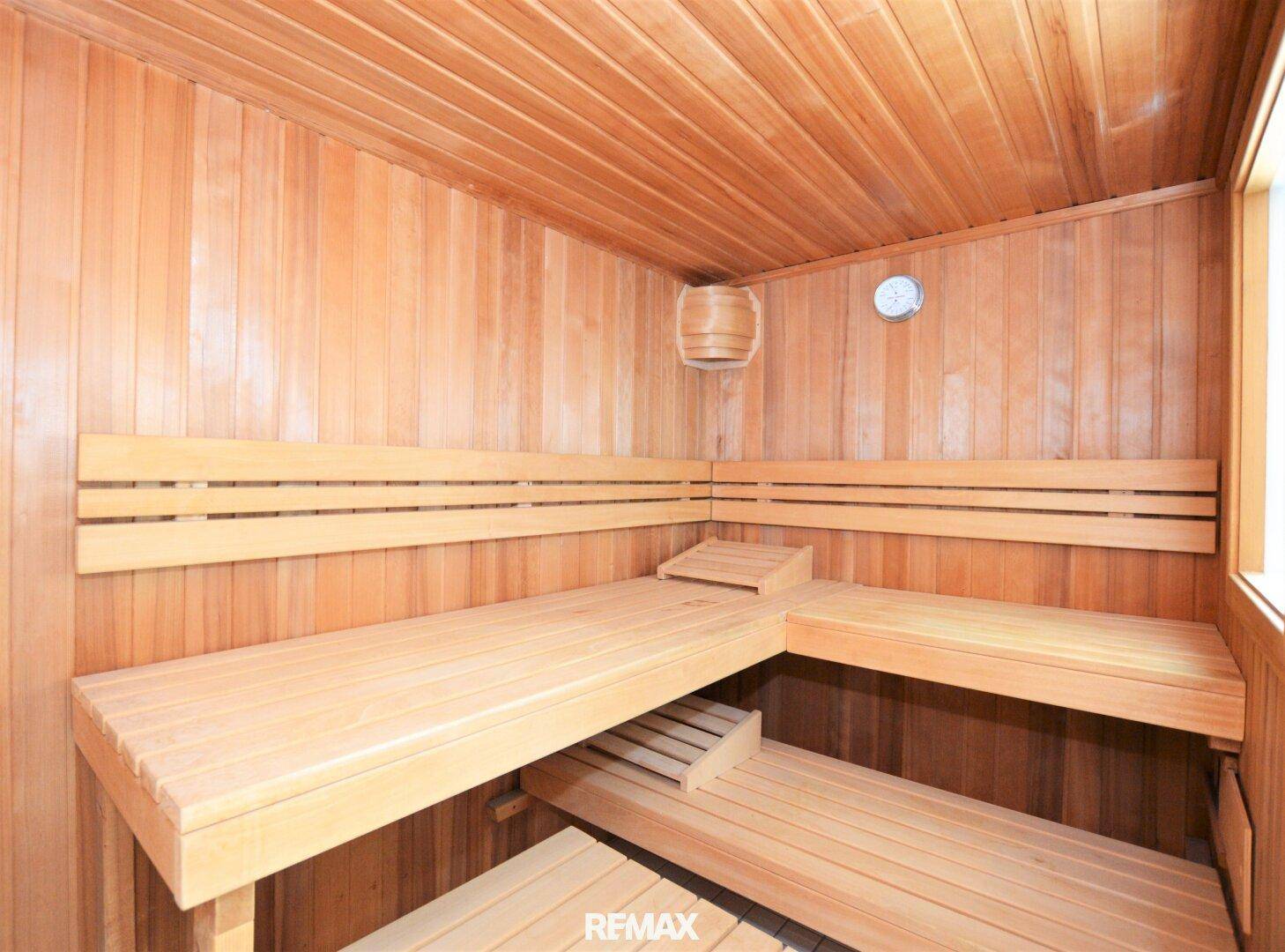 Innenansicht einer traditionellen Holzsauna mit mehreren Sitzebenen und klassischem Ofen.