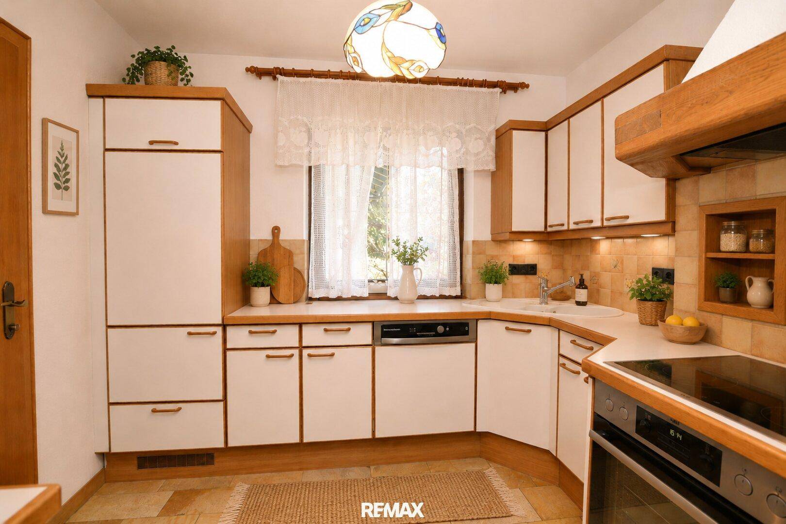 Funktionale Küche im Landhausstil mit weißen Schränken, Holzdetails und Fenster.
