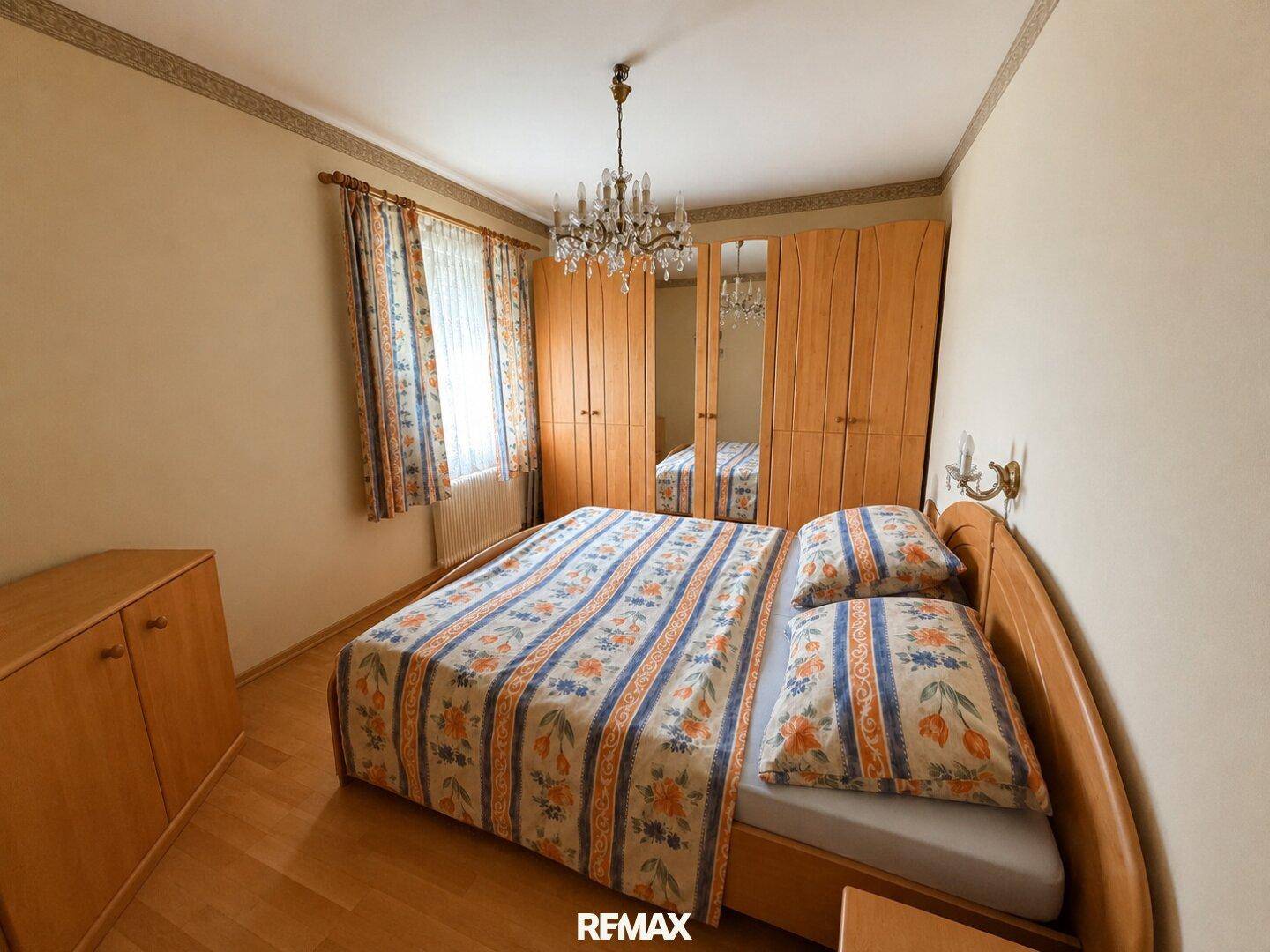 Schlafzimmer mit Holzboden, Spiegelschränken und traditionellem Doppelbett.