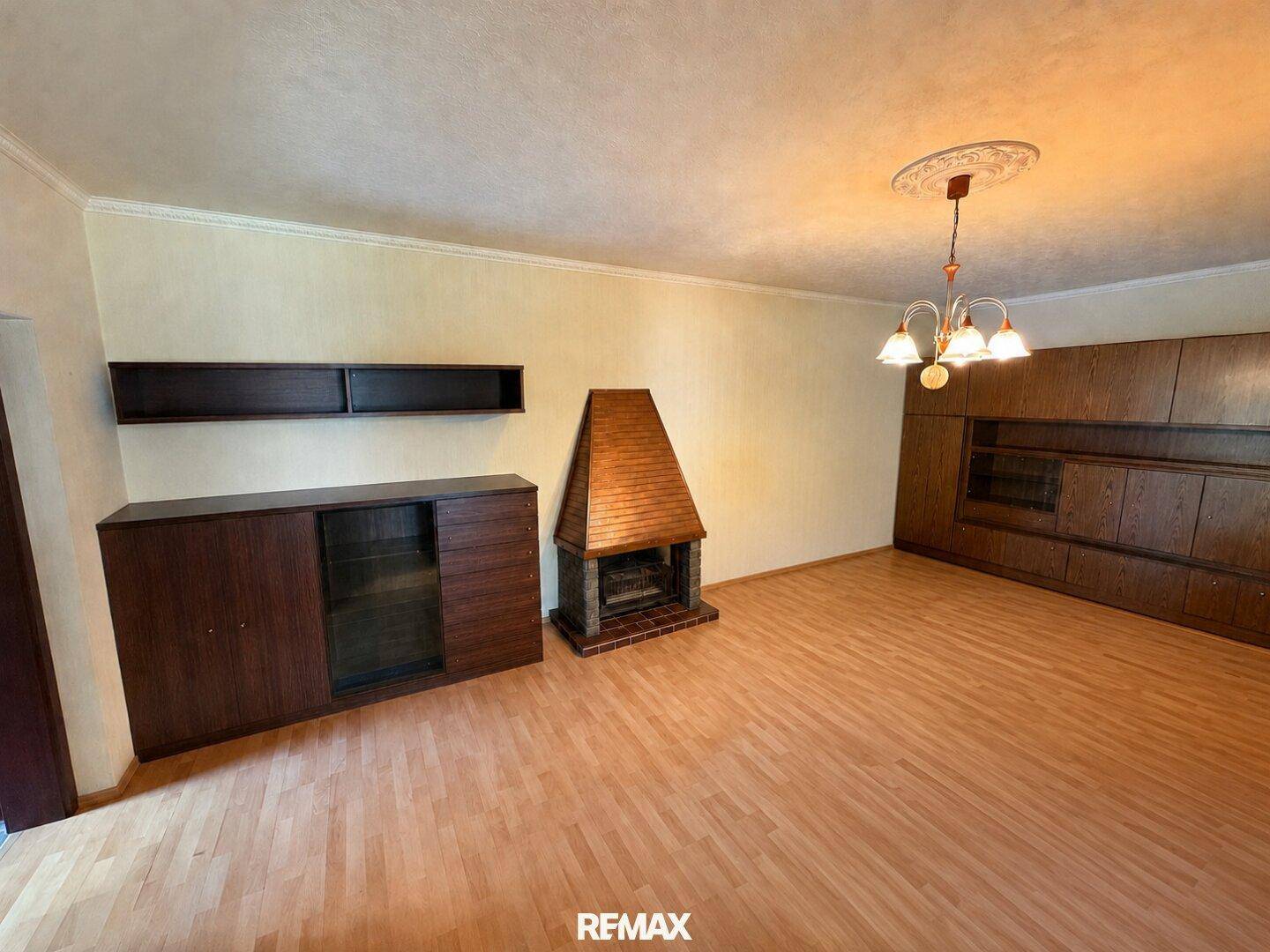 Geräumiges Wohnzimmer mit Parkettboden, Kamin und traditionellen Holzmöbeln.