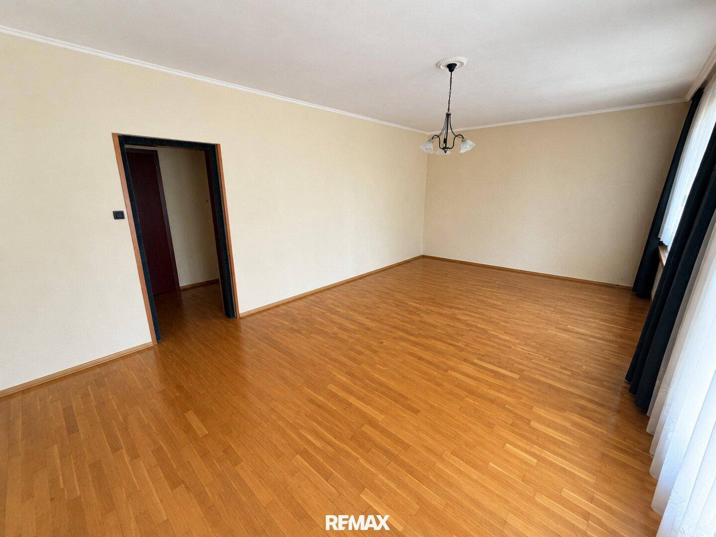 Leerer Raum mit Parkettboden und Zugang zu einem weiteren Zimmer.