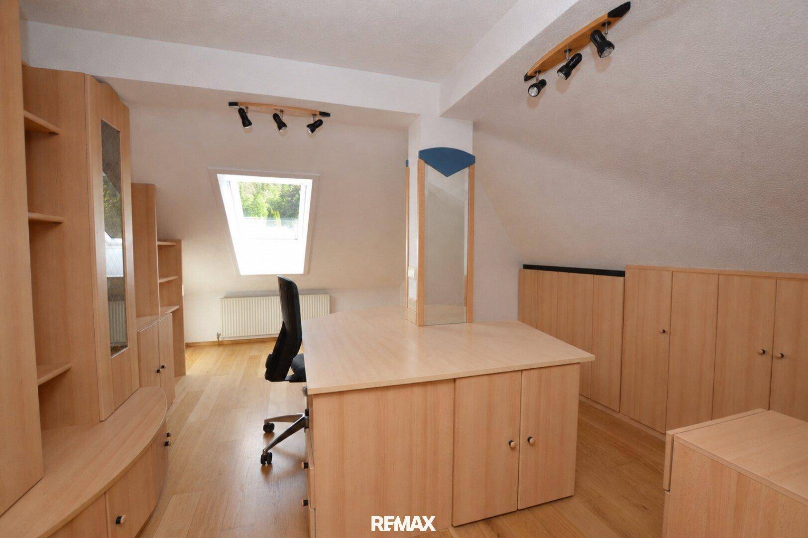 Dachgeschoss-Büro mit Schreibtisch, Stauraum und Dachfenster für natürliches Licht.