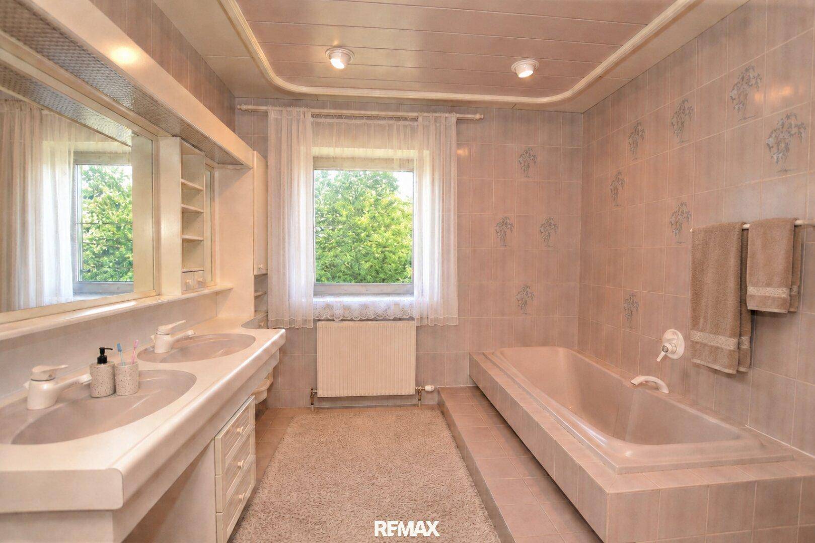 Geräumiges Badezimmer mit Doppelwaschbecken, Einbaubadewanne und Fenster.