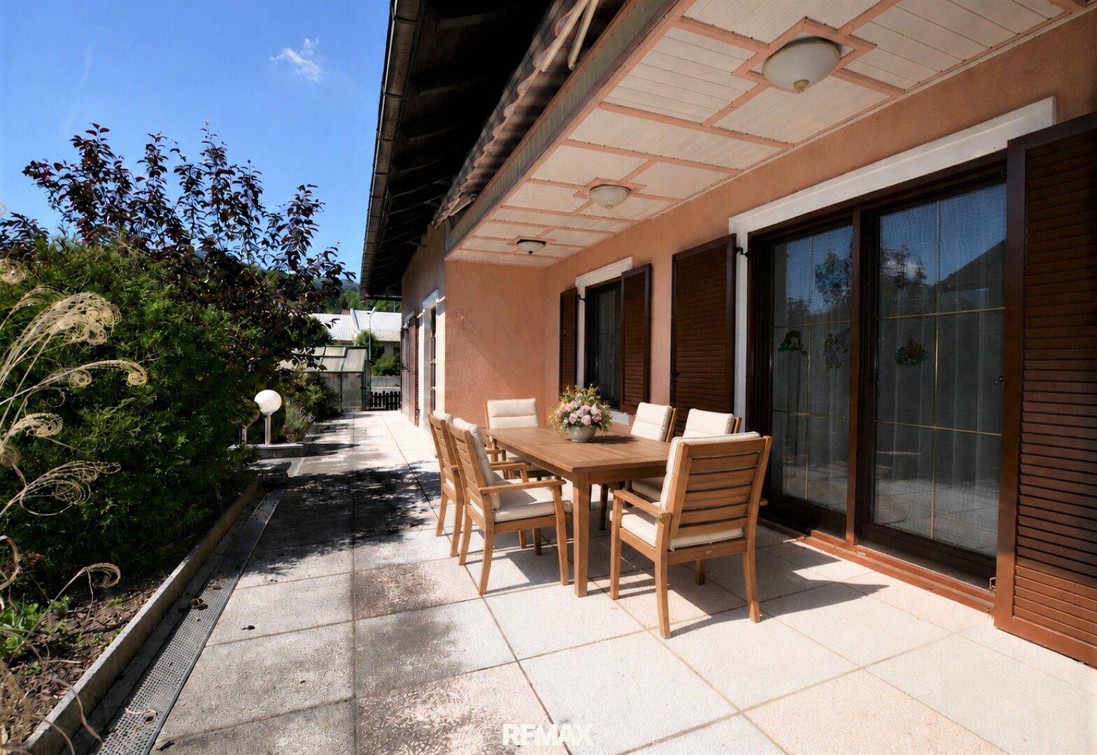 Geräumige Terrasse mit Holztisch und Stühlen, ideal für Mahlzeiten im Freien.