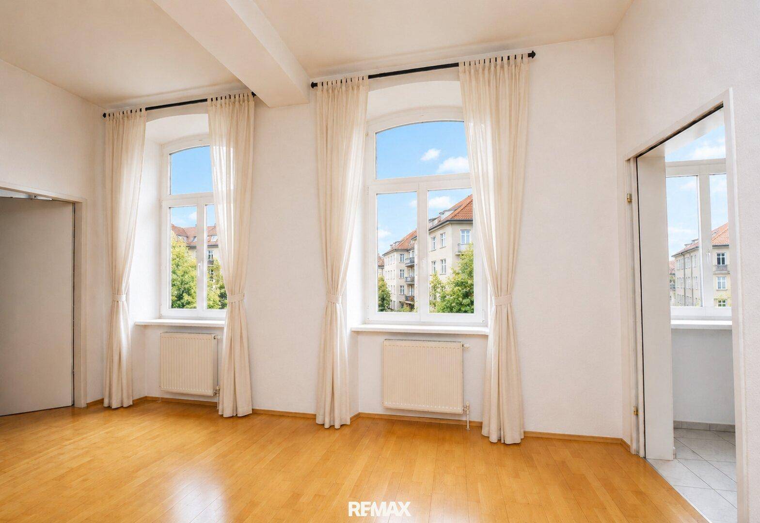 Geräumiger Essbereich mit Holzboden, hohen Fenstern und Blick auf die umliegenden Gebäude.