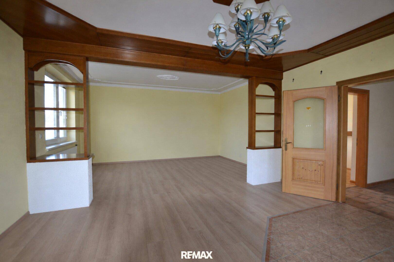 Helles Wohnzimmer mit Holzelementen und integrierten Regalen, bereit zur individuellen Gestaltung.