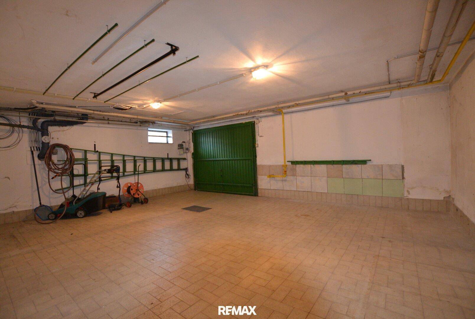 Geräumige Garage im Kellergeschoss mit grünem Tor und Stauraum.