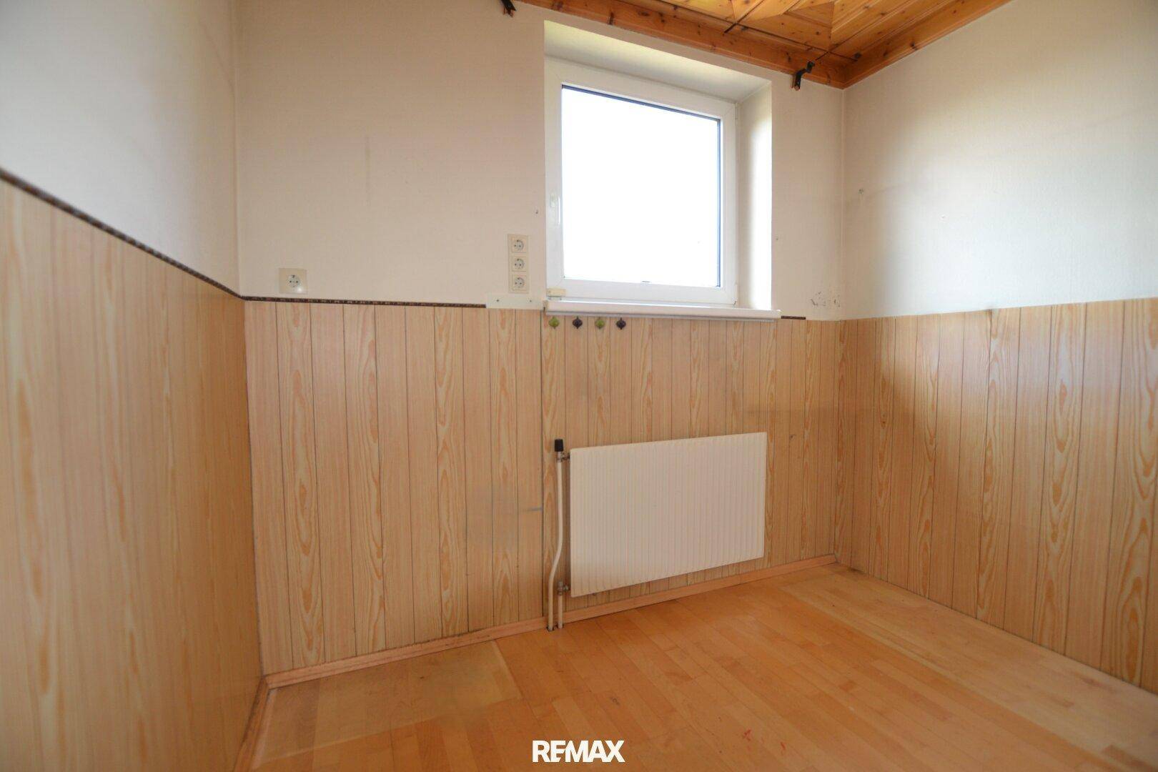 Kleiner Raum mit Holzvertäfelung und Fenster, ideal als Abstellraum oder Büro.
