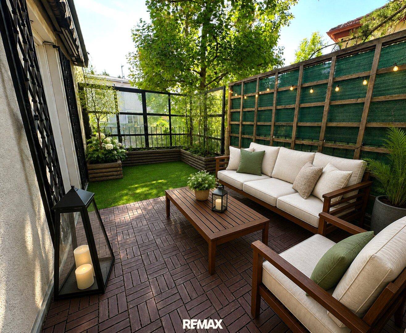 Gemütliche Terrasse mit Gartenmöbeln, Kunstrasen und stimmungsvoller Beleuchtung.