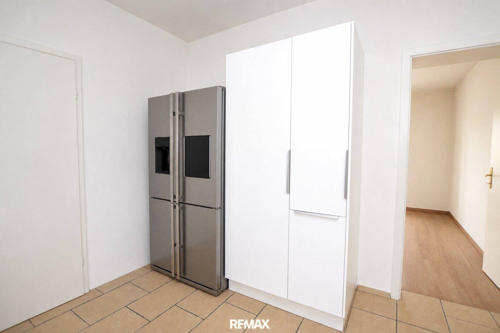 Küchenbereich mit großem Kühlschrank im amerikanischen Stil und weißen Hochschränken.