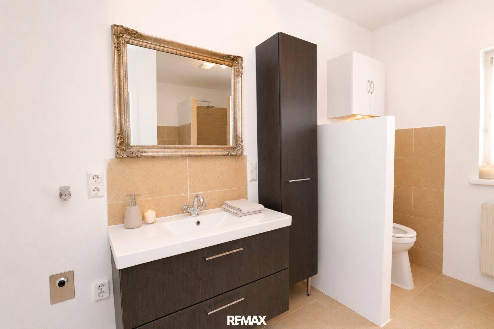 Modernes Badezimmer mit Einzelwaschbecken, Spiegelschrank und separatem WC-Bereich.