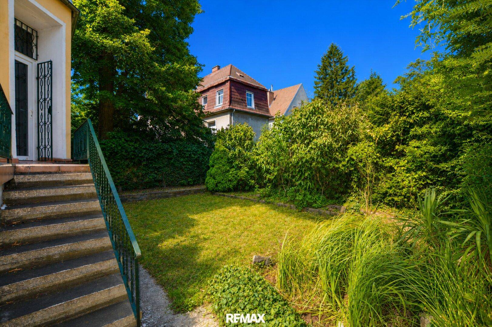 Gepflegter Gartenbereich mit Steintreppe und üppiger, grüner Bepflanzung im Freien.