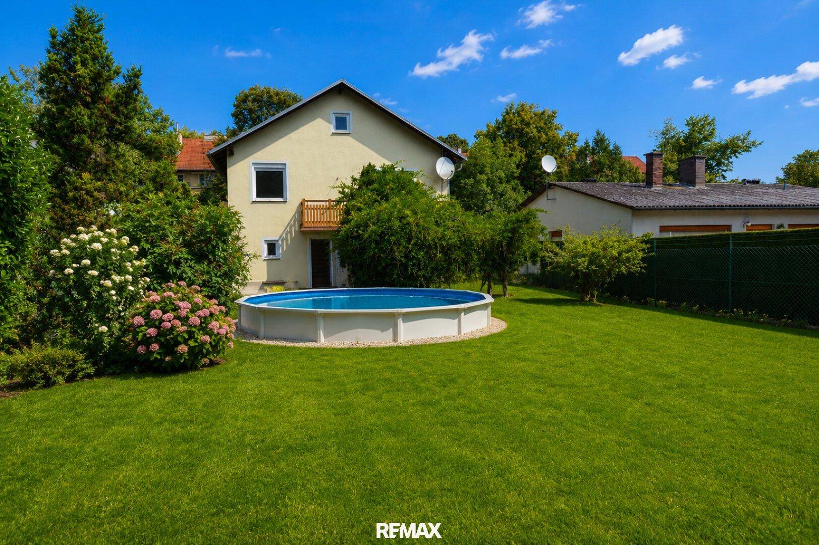 Weitläufiger Garten mit Aufstellpool und Blick auf die Rückseite des Hauses mit Balkon.