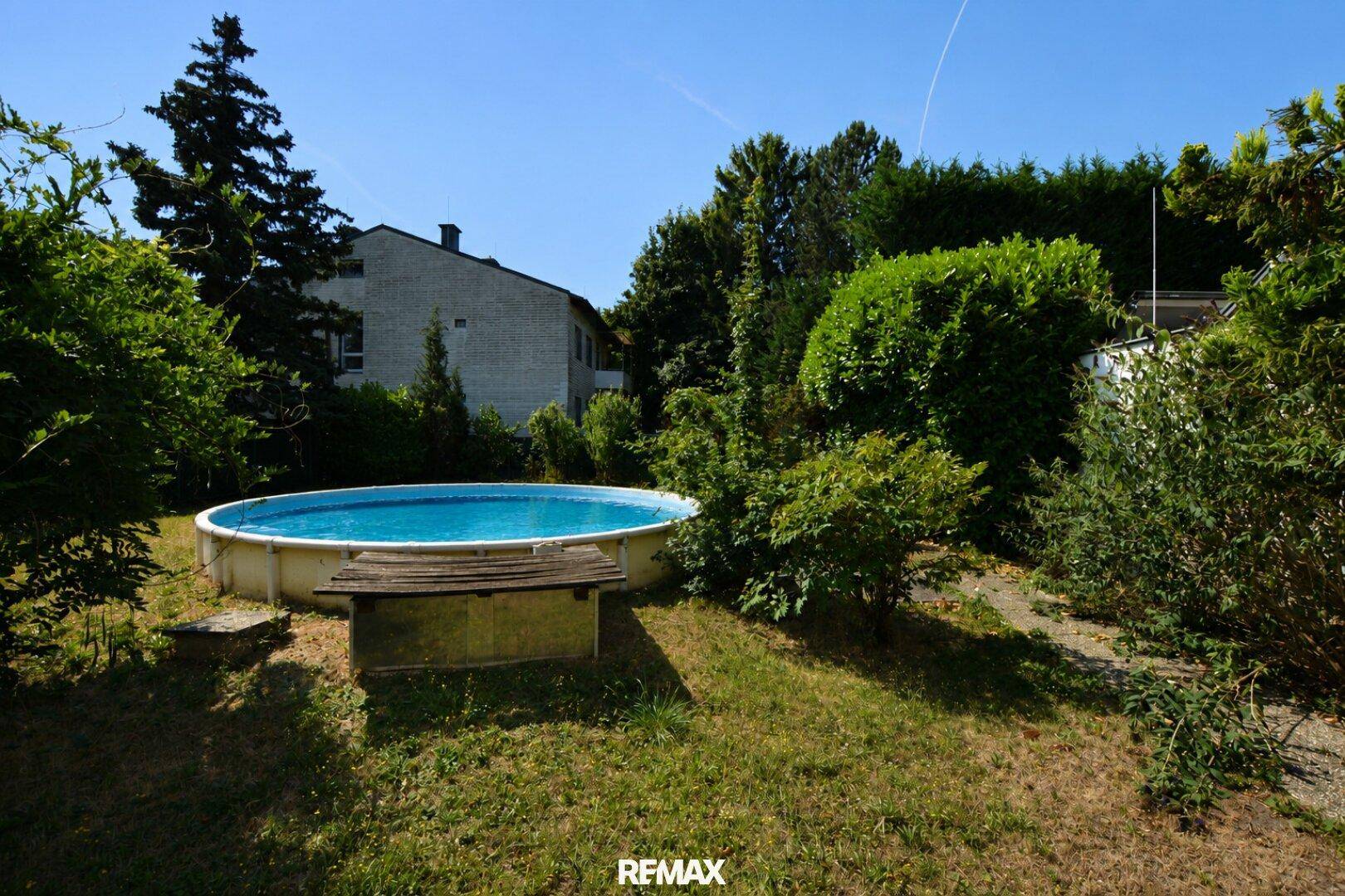 Großer Gartenbereich mit Aufstellpool und viel Grünfläche an einem sonnigen Tag.