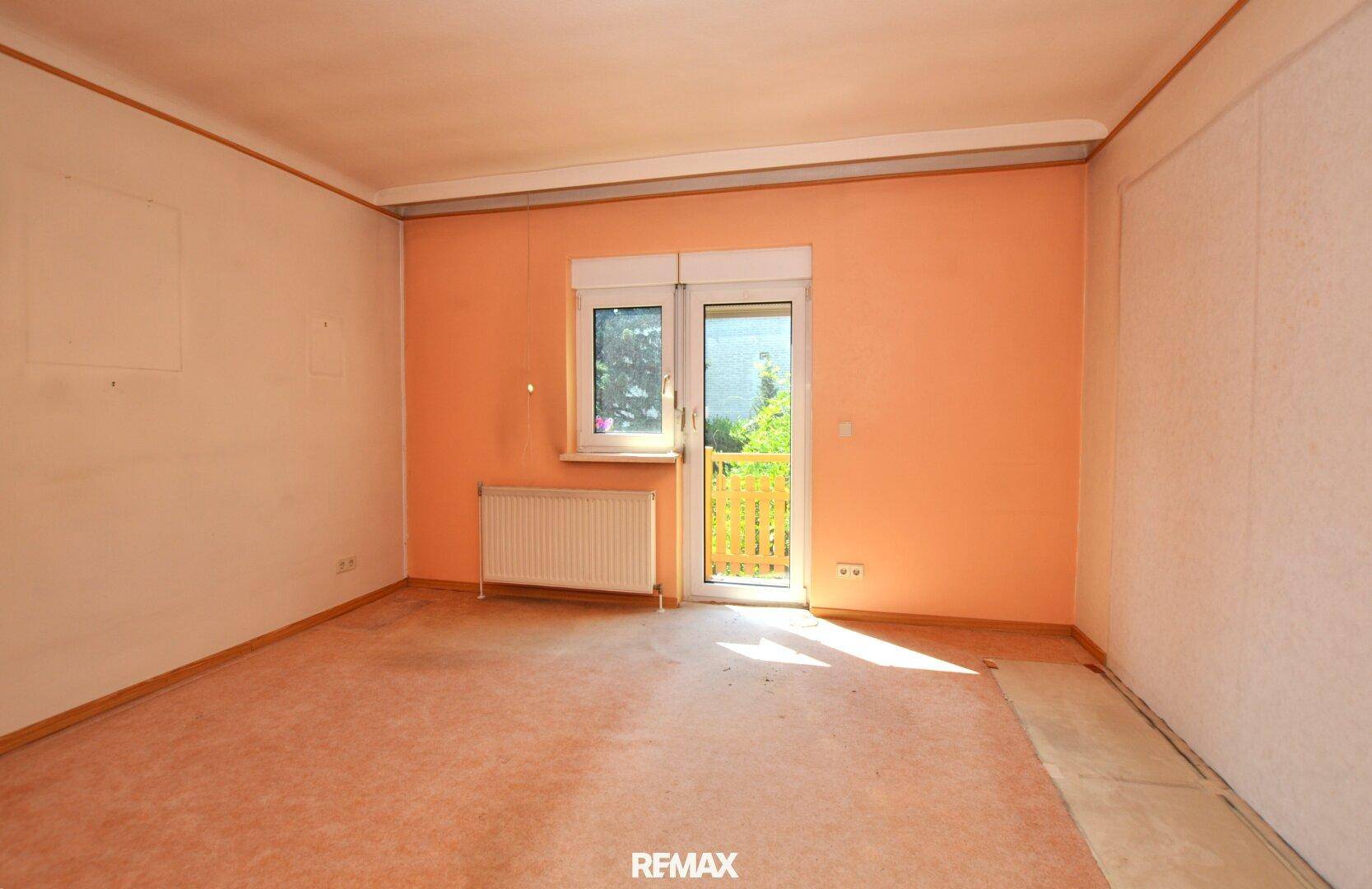 Schlafzimmer in ursprünglichem Zustand mit Teppichboden und Zugang zum Balkon.