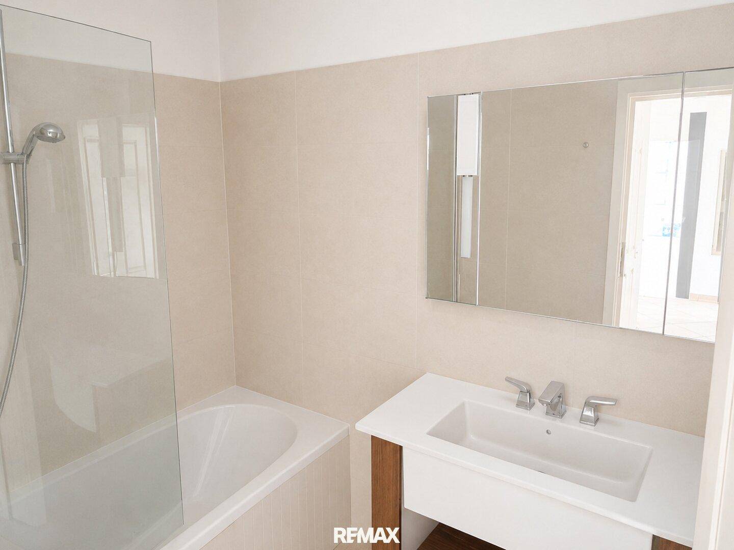 Modernes Badezimmer mit Badewanne, Duschabtrennung und Waschtisch mit Spiegelschrank.