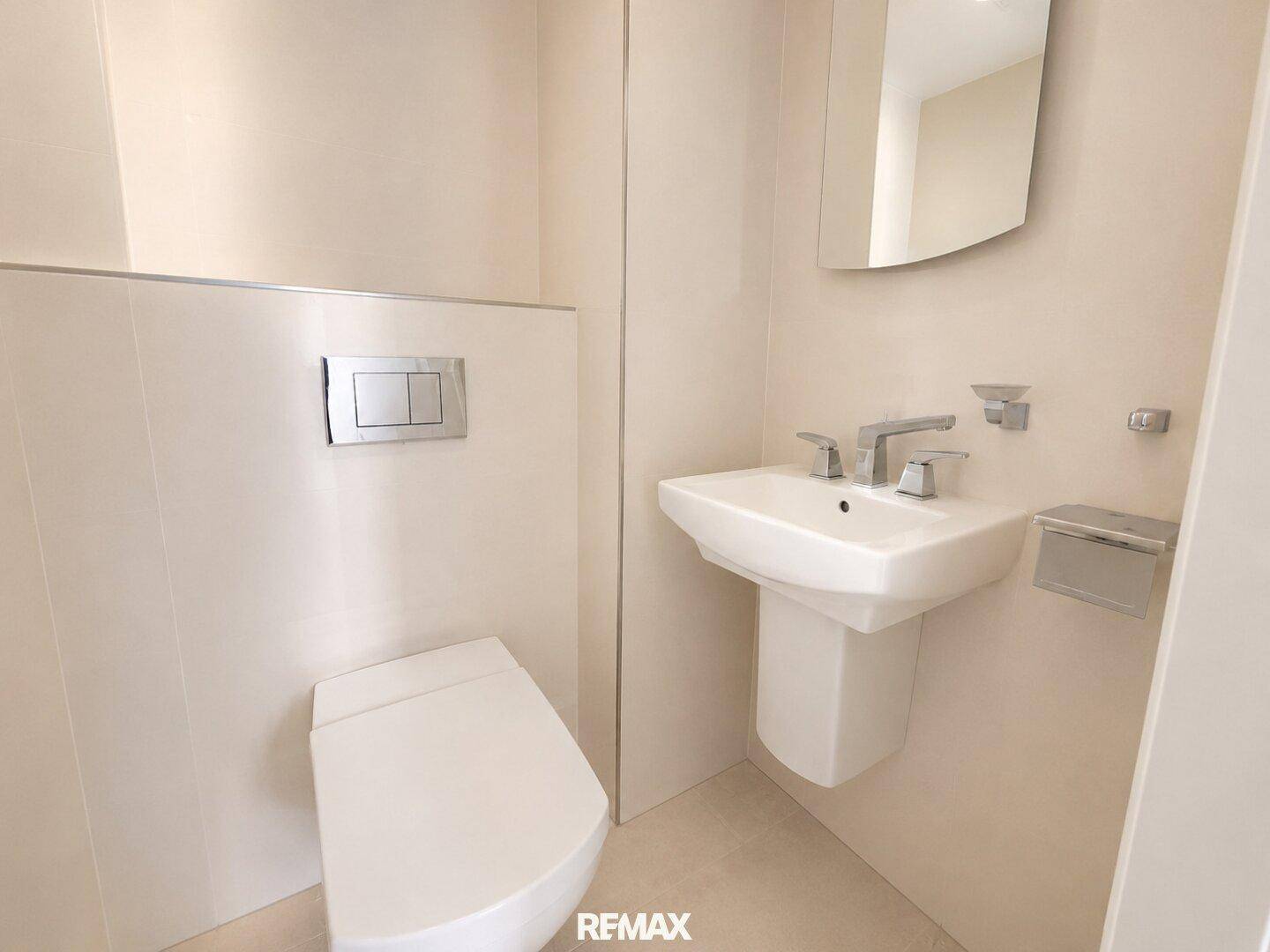Separates Gäste-WC mit wandhängender Toilette und kleinem Waschbecken.
