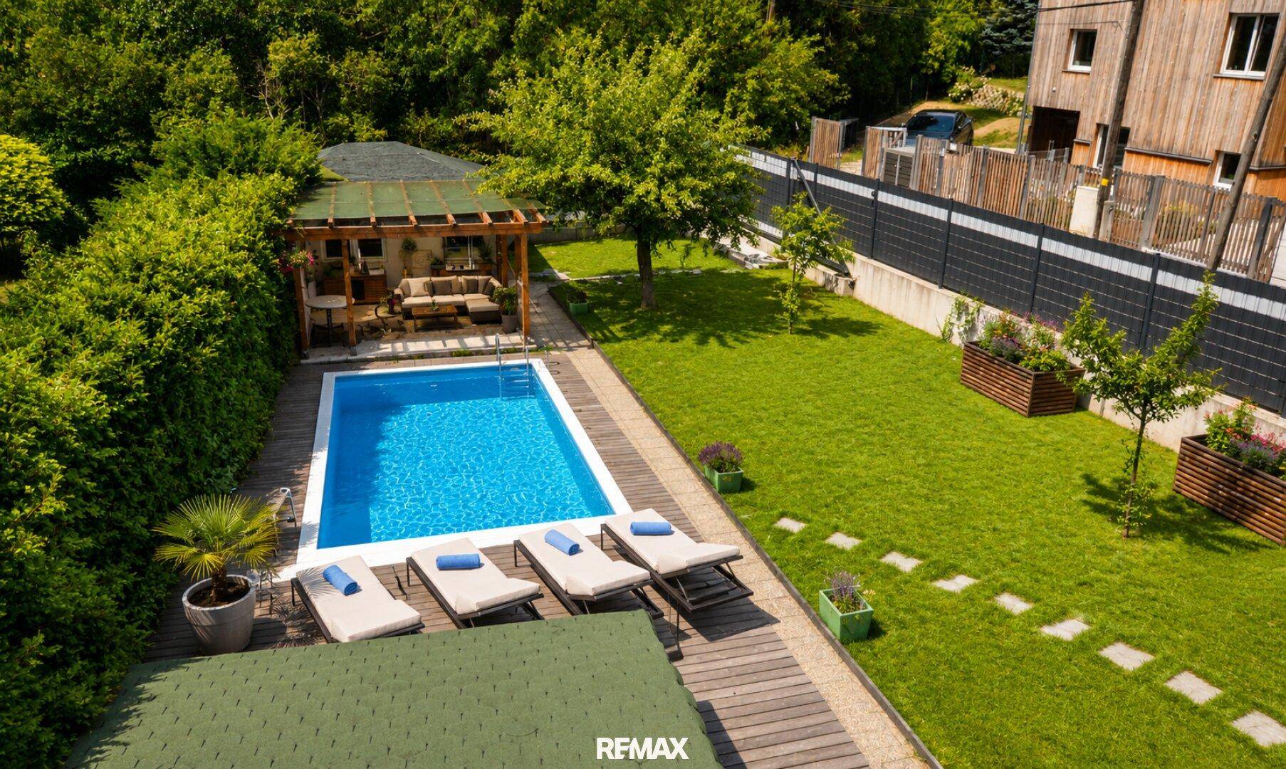 Vogelperspektive des Gartens mit Pool, Pergola und angrenzendem Holzhaus.