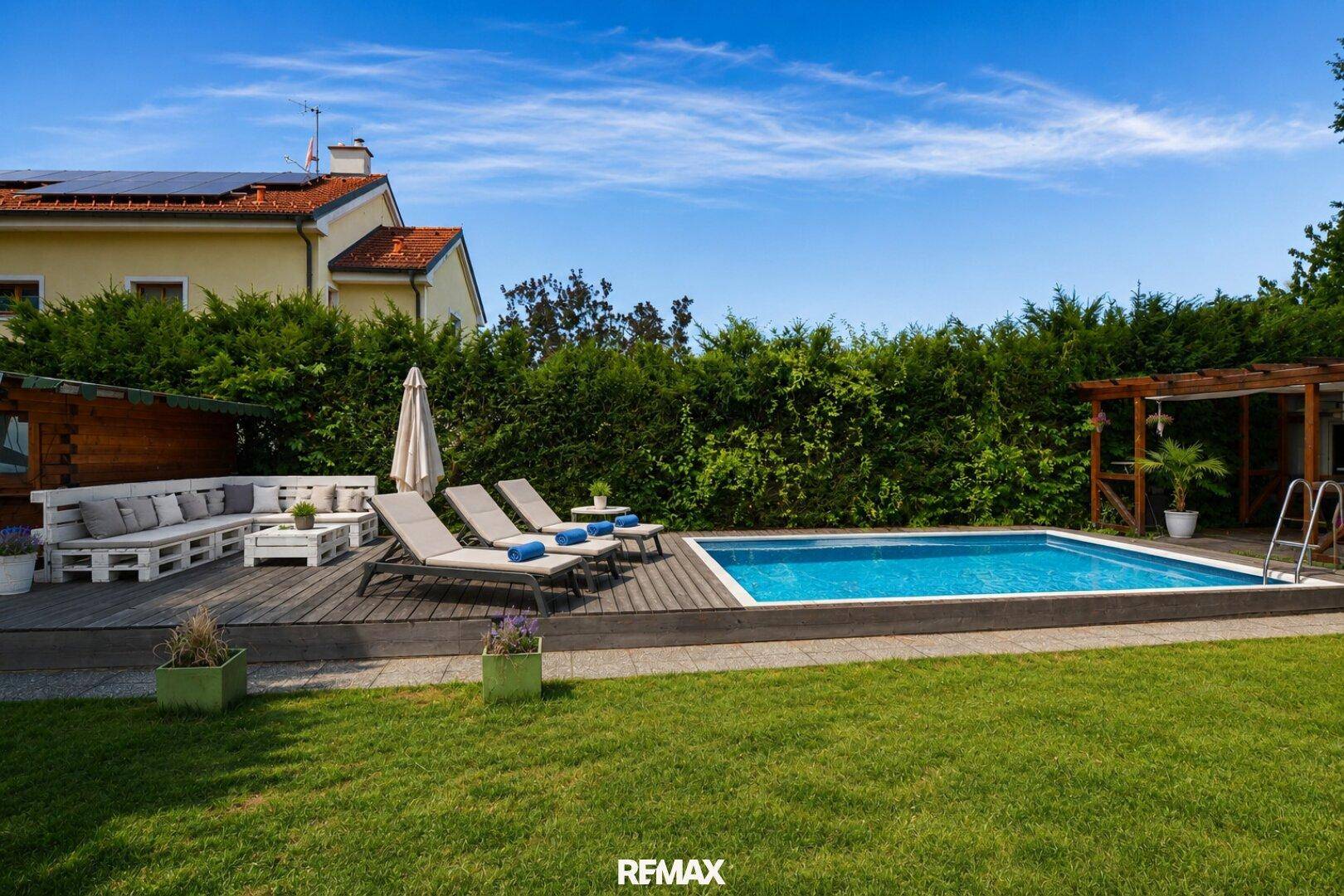 Gepflegter Gartenbereich mit Swimmingpool, Holzdeck und bequemen Liegestühlen.