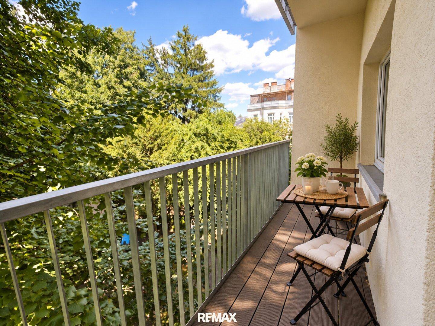 Gemütlicher Balkon mit Holzboden, Sitzgelegenheiten und üppigem Grünblick, ideal zum Entspannen.