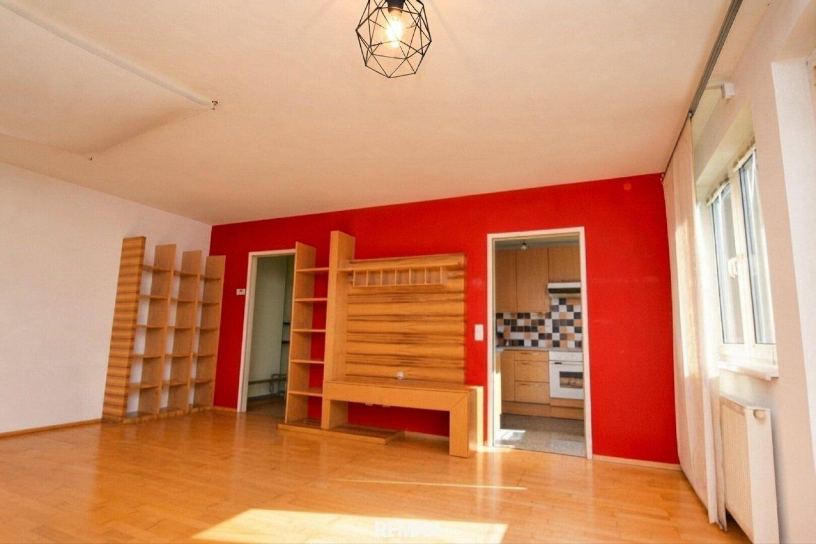 Wohnzimmer mit Holzboden und Blick auf die angrenzende Küche.