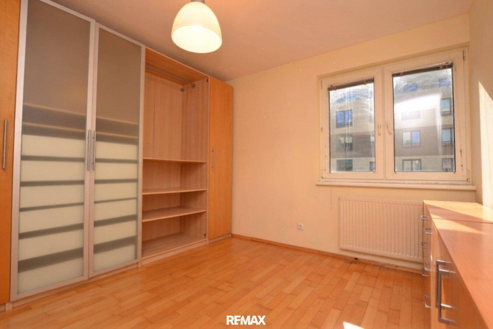 Helles Schlafzimmer mit großem Fenster und praktischem Kleiderschrank.