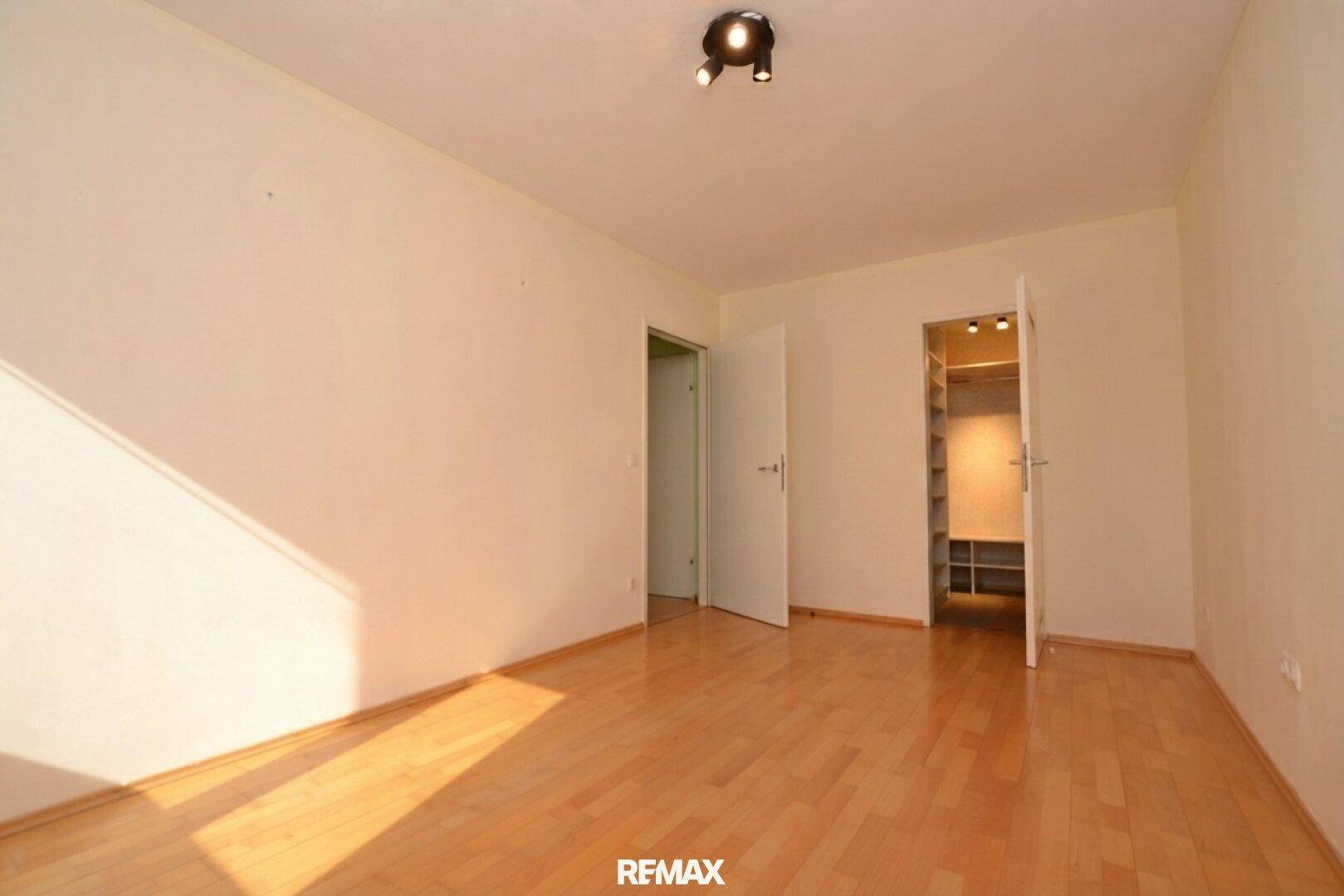 Leeres Schlafzimmer mit Parkettboden und begehbarem Kleiderschrank.