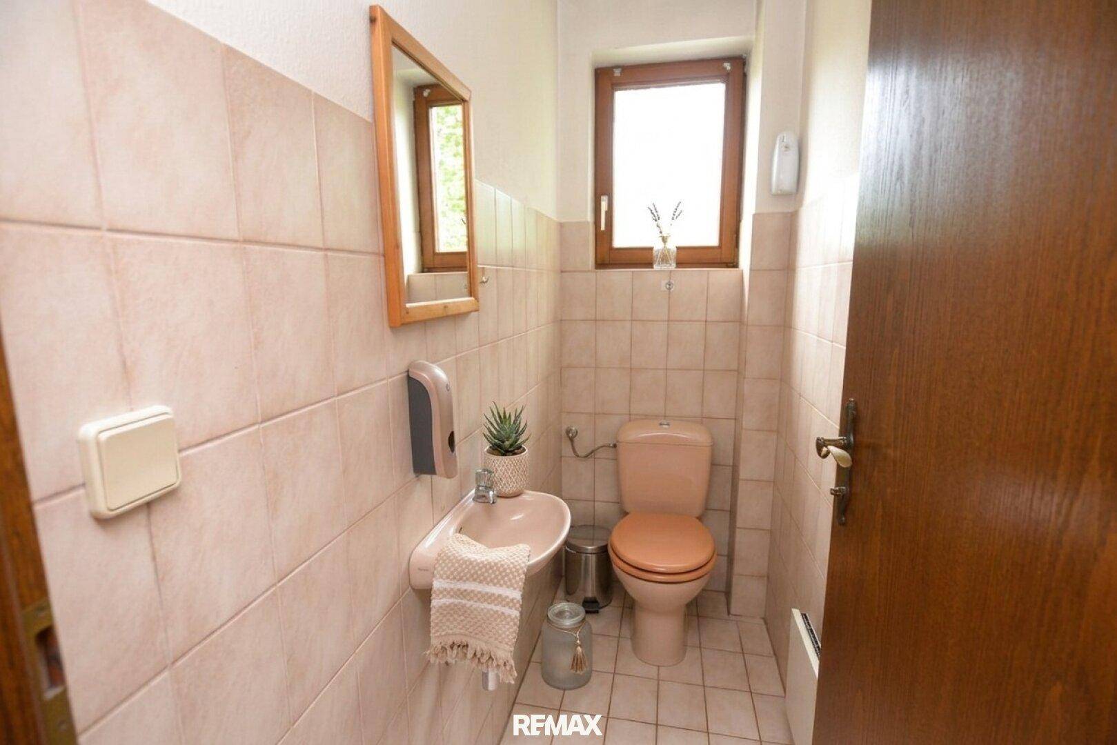Kleines Gäste-WC mit beigefarbenen Fliesen, Toilette und Waschbecken.