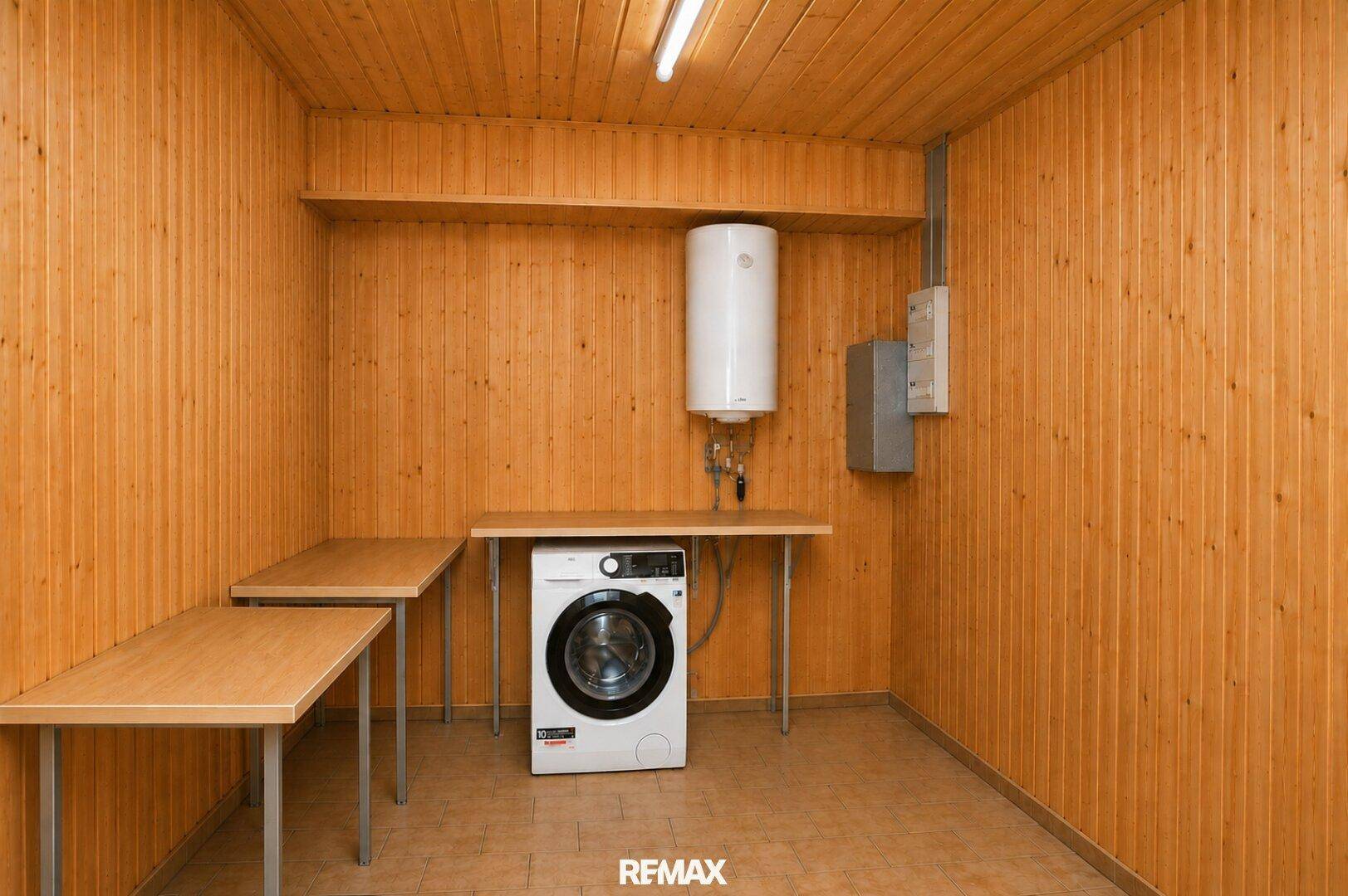 Hauswirtschaftsraum mit Holzverkleidung, Waschmaschine und Warmwasserbereiter.