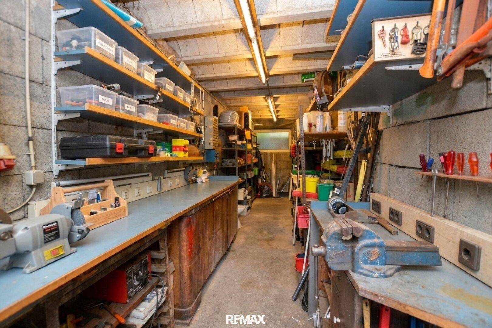Werkstatt oder Lagerraum im Keller mit Regalen, Werkzeugen und Betonwänden.