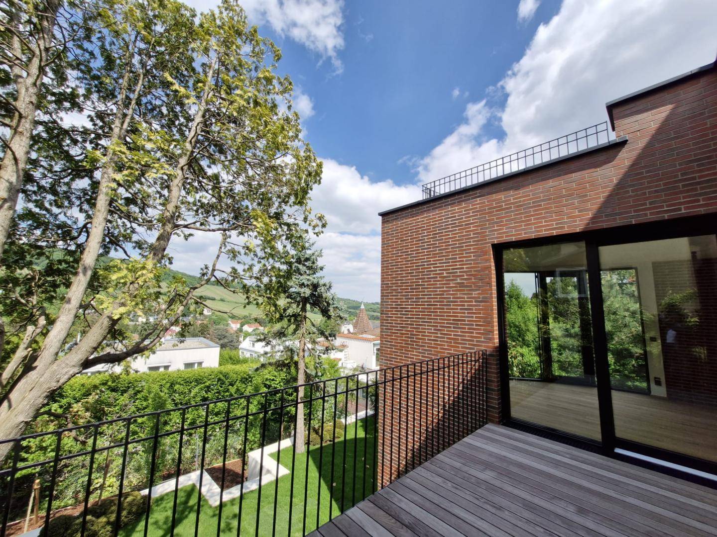 Balkon mit Holzboden und Blick auf den Garten sowie die umliegende Landschaft.