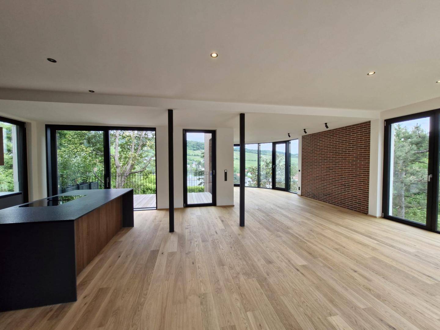Heller, offener Wohnbereich mit Holzboden, Ziegelwand und Zugang zu Balkon/Terrasse.