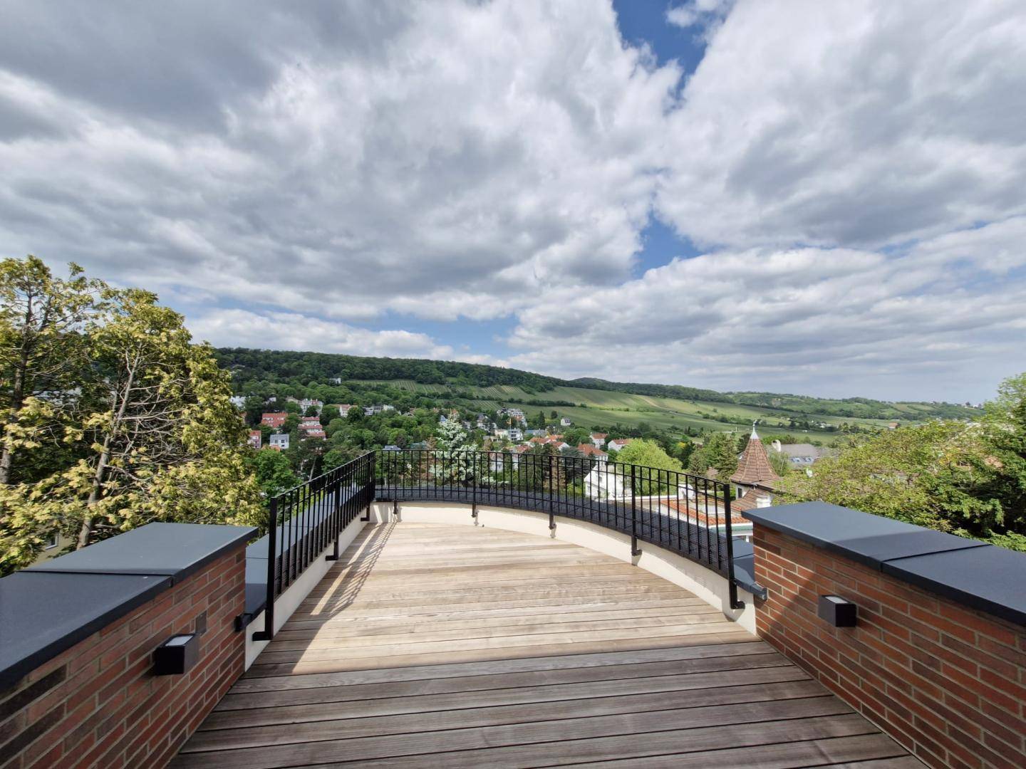 Große Holzterrasse mit Geländer und weitem Blick über die grüne Landschaft.
